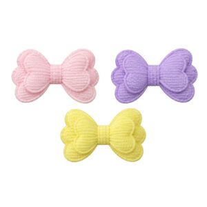 Três apliques em formato de laço duplo, com textura canelada, nas cores rosa-claro, lilás e amarelo-claro.