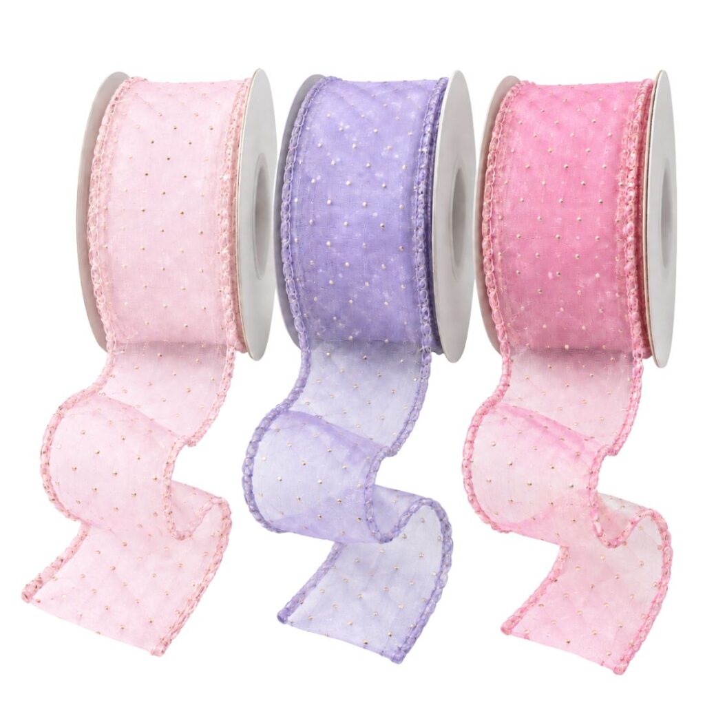 Fita de organza com poá dourado e bordas decoradas, nas cores rosa-bebê, lilás e rosa.