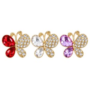 Aplique de borboleta dourada com strass e pedras na cor vermelho, branco e lilás sobre fundo branco.