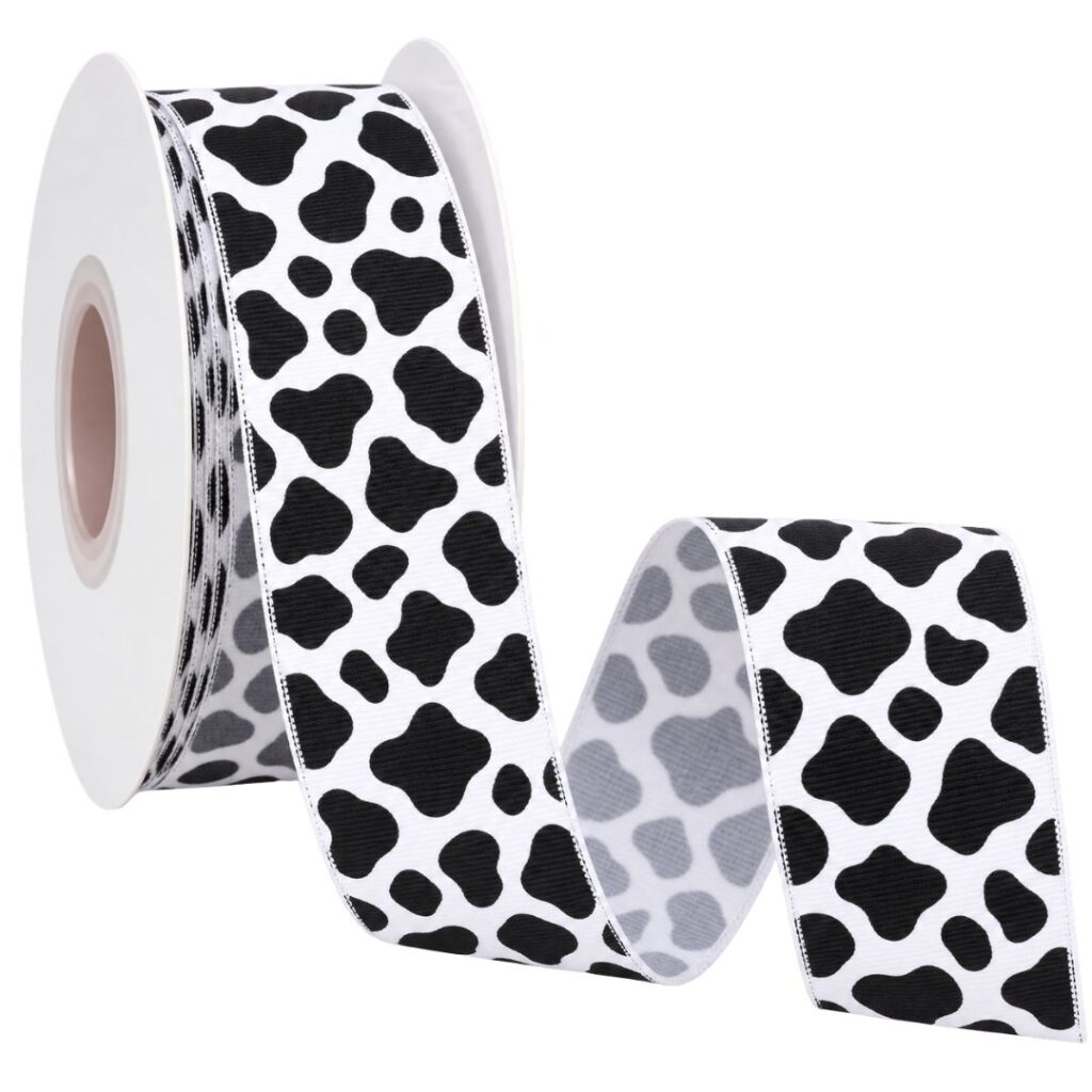 Rolo de fita de gorgurão branca com estampa animal print em preto, parcialmente desenrolado.